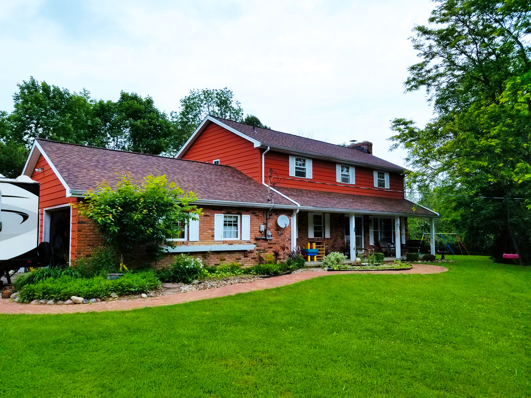 Brand New Roof Installation Red house with lush green front lawn and new roofing shingles.