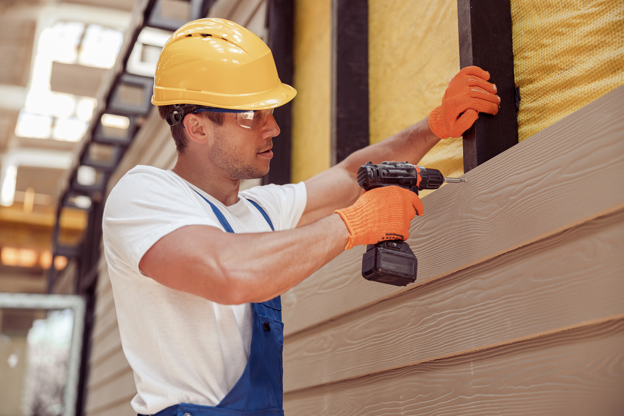 Construction Worker installing a vinyl siding to a houses frame